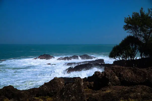 Photo of A panoramic view of rocky coastline hits by the wave.