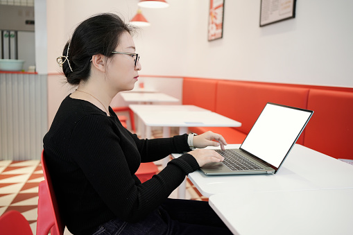 A young businesswoman uses a laptop in a restaurant