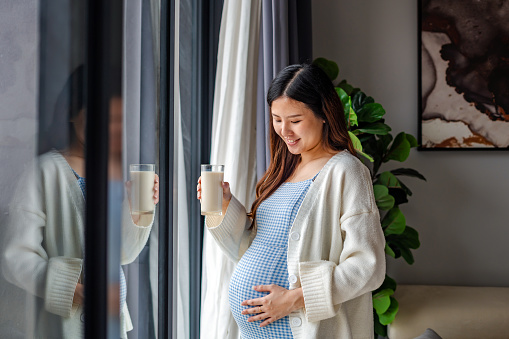 Portrait of a beautiful pregnant woman holding glass of milk, healthy lifestyle concept