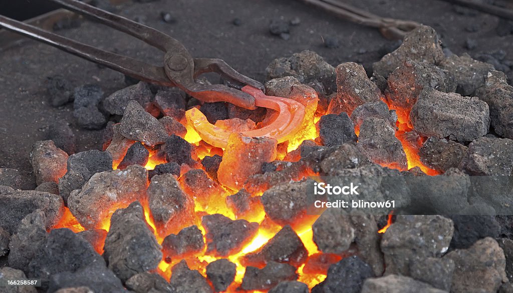 Artisan Forgeron réchauffement un fer à cheval de fer dans le feu - Photo de Acier libre de droits