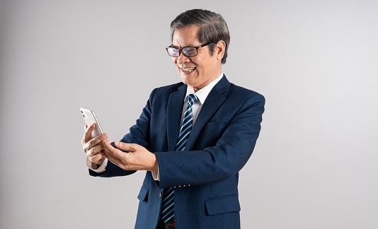 Portrait of an elderly Asian businessman, posing on a blue background