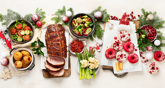 Concept of Christmas or New Year dinner with roasted meat and various vegetables dishes on a white background. Top view.