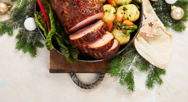 istock Roasted sliced Christmas ham on plate with vegetables, festive decoration. 1662629887