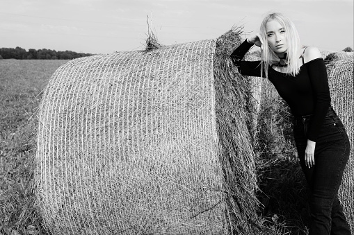Field. The woman lies on the hay in the field.