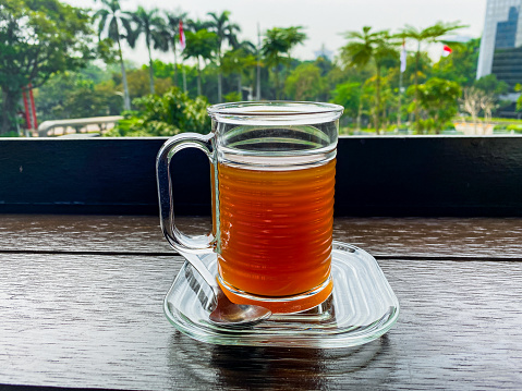 a glass of hot tea on a wooden table and a view of the green garden in the office area