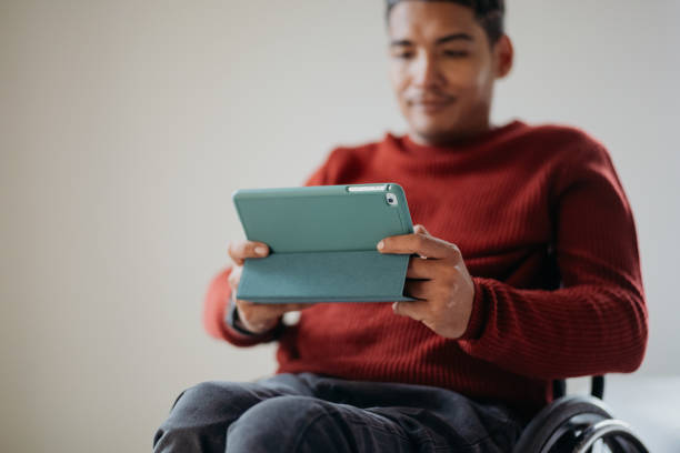 istock Disabled asian man in a wheelchair using digital tablet at home 1662674641
