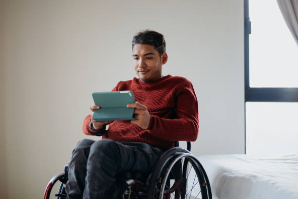 istock Disabled asian man in a wheelchair using digital tablet at home 1662674642