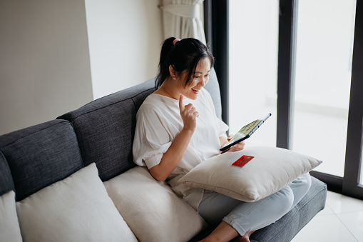 An Asian Chinese woman using digital tablet online shopping at home
