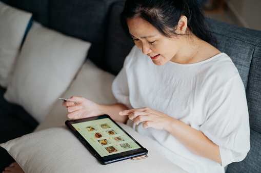 An Asian Chinese woman ordering food delivery with digital tablet