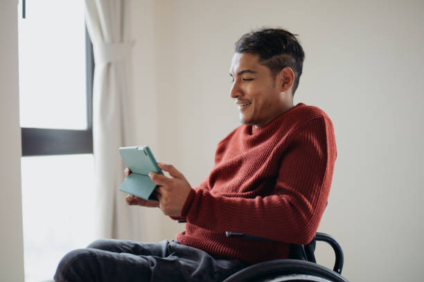 istock Disabled asian man in a wheelchair using digital tablet at home 1662674653
