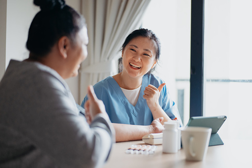 An Asian Chinese female doctor telling good news to her senior patient during a healthcare house call