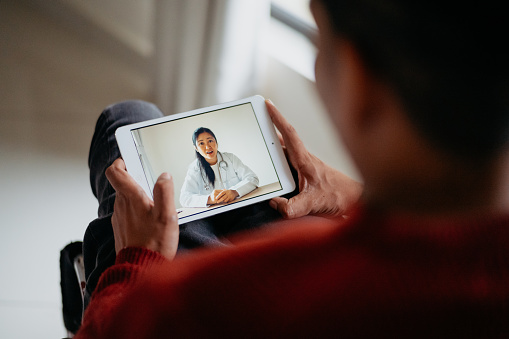 Disabled asian man in a wheelchair video conference with doctor on digital tablet