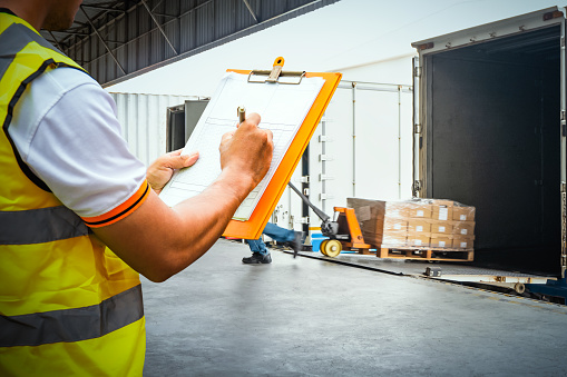 Worker Holds a Clipboard Checking the Loading Package Boxes at Distribution Warehouse. Delivery Shipment to Customers. Supplies Warehouse Shipping, Freight Truck Logistic Transport.