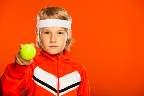Competitive tennis kid, isolated on orange.