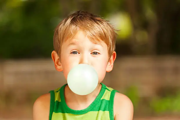 Cute little boy blowing big bubble with gum.