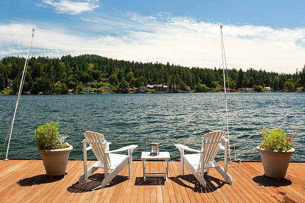 Adirondacks on lakeside Deck Two adirondack chairs on lakeside deck. holiday camp stock pictures, royalty-free photos & images