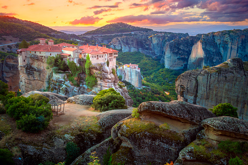 Holy Meteora. Greece, Meteora Monasteries. Panoramic view of the Holy Monastery of Varlaam, located on the edge of a high cliff. Beautiful sunrise. The Meteora Monasteries area is listed as a UNESCO World Heritage Site. Greece, Europe
