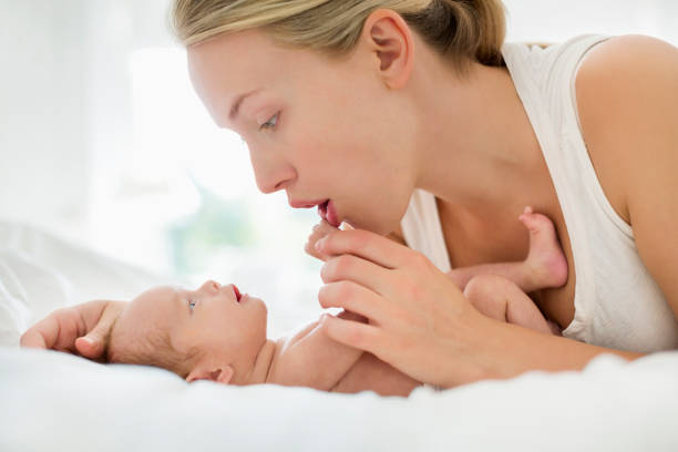 istock Mother cradling newborn infant on bed 166272545