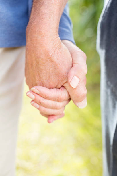 pareja de ancianos sosteniendo las manos al aire libre - hands in the middle fotografías e imágenes de stock