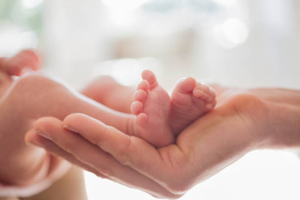 istock Mother cradling newborn baby's feet 166272556