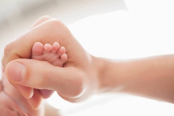istock Mother cradling newborn baby's foot 166272614
