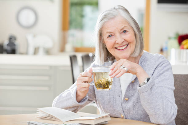 edad mujer bebiendo té y lectura - infusión té bebida fotografías e imágenes de stock