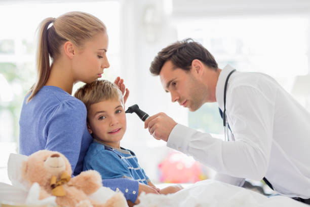 istock Doctor examining boy's ear at house call 166272638