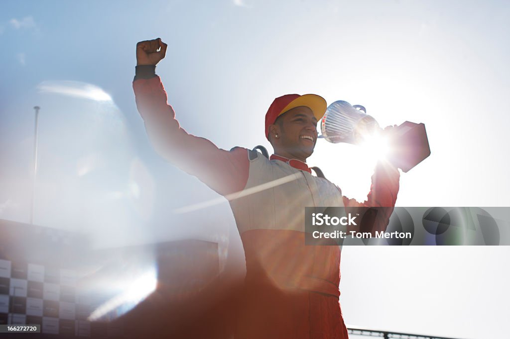 Cheering racer holding trophy on track  Race Car Driver Stock Photo