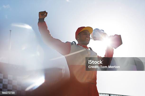 Cheering Racer Holding Trophy On Track Stock Photo - Download Image Now - Race Car Driver, Trophy - Award, Winning