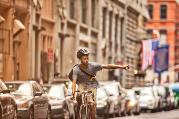 homme équitation un vélo dans la ville rue - geste de la main photos et images de collection