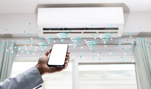 istock Hand holding smartphone with white screen and wifi network with air conditioner background 1662763349