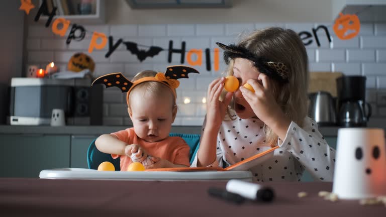 Baby girl playing with older sister on Halloween