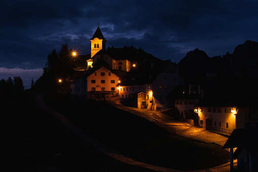 View of small Italian mountain village at night; bright street lights lit buildings