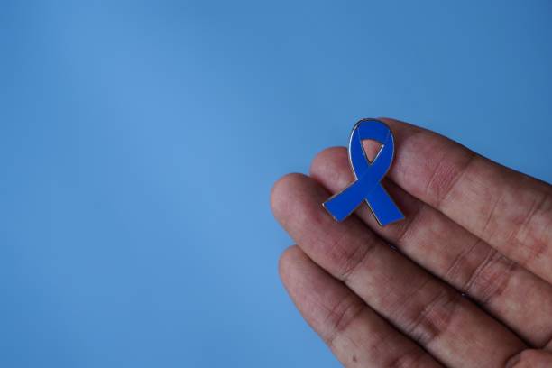 istock Hand holding blue ribbon on blue background with copy space. 1662838401