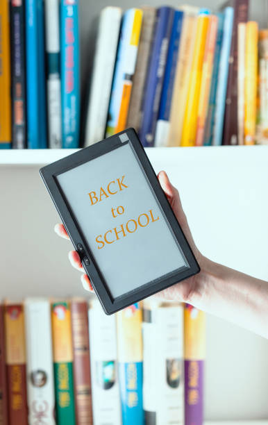 istock Hand  holding e-book  reader device against  the book closet with BACK TO SCHOOL word, return to colleage cocnept. 1662850422