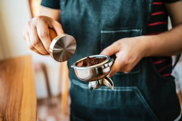 istock Hand Barista cafe making coffee with manual presses ground coffee using a tamper at the coffee shop, Barista holding a portafilter  making an espresso coffee 1662850968