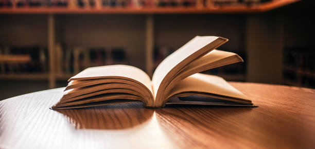 istock Vintage style.An open book or textbook vintage style in the library with light from the window on the reading table and the corridor of the bookshelves in the school classroom background.Education learning concept 1662852172