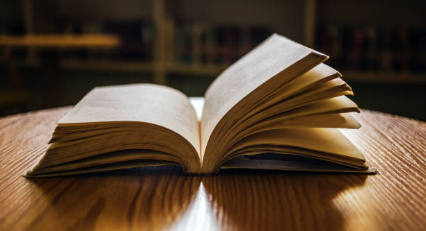 istock Vintage style.An open book or textbook vintage style in the library with light from the window on the reading table and the corridor of the bookshelves in the school classroom background.Education learning concept 1662852183
