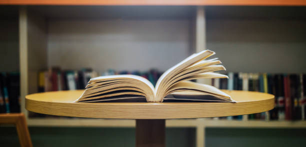 istock Vintage style.An open book or textbook vintage style in the library with light from the window on the reading table and the corridor of the bookshelves in the school classroom background.Education learning concept 1662852711