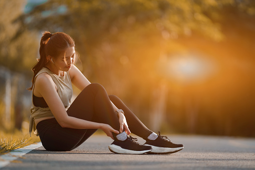 Beautiful sporty woman holding injured legs in the park, Healthy lifestyle and sport.