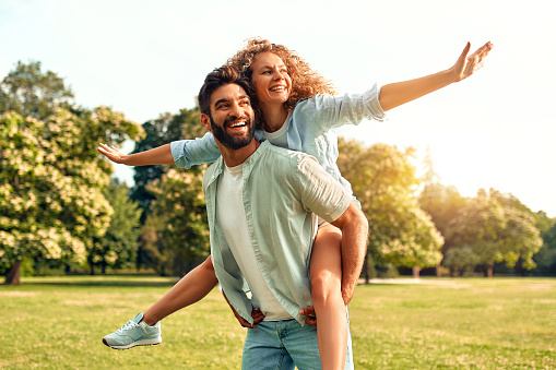 Happy young couple in love romantically spending time together in a meadow in a park on a warm sunny weekend.