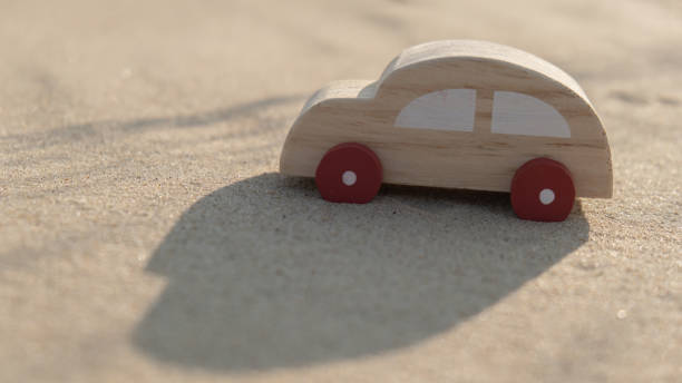 Wooden toy car on sandy beach background. Eco-friendly travel, reduce carbon footprints, environmental impact, Conscious Traveler, Environmentally Friendly, responsible traveler Eco-car concept World car free day. Roadtrip local travel coche de juguete de madera sobre fondo de playa de arena. viajes ecológicos, reducir la huella de carbono, impacto ambiental, viajero consciente, respetuoso con el medio ambiente, viajero responsable concepto de coche ecológico día mundial sin coches