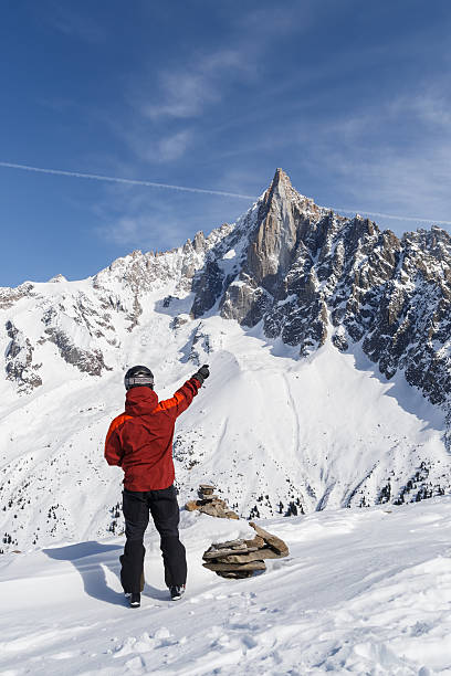 Skier pointing towards mountain peak stock photo