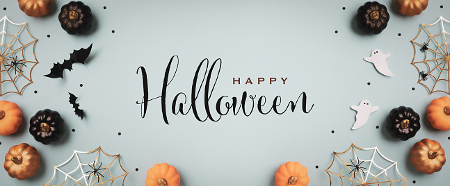 Halloween holiday background with party decorations from  pumpkins, bats, ghosts, spider webs on blue top view. Greeting card with text inscription Happy Halloween in banner format.