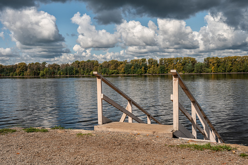 A wooden staircase with a railing leading down to the water's edge.