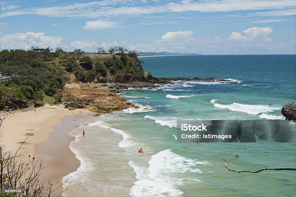 Coolum Beach First Bay Rocky and sandy bay at Coolum, Queensland, Australia. Midground featuring Point Arkwright. White breaking surf with some swimmers. Beautiful sunny day with clear blue sky. Ocean is deep blue and turquoise colour. Coolum Beach Stock Photo