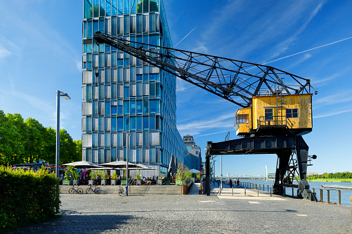 The revitalized rheinauhafen urban district along the former industrial port of Cologne. Located in the south of Cologne, various modern office buildings line up along the Rhine. A pedestrian promenade invites you to take a stroll. A restored crane points to the history of the place.