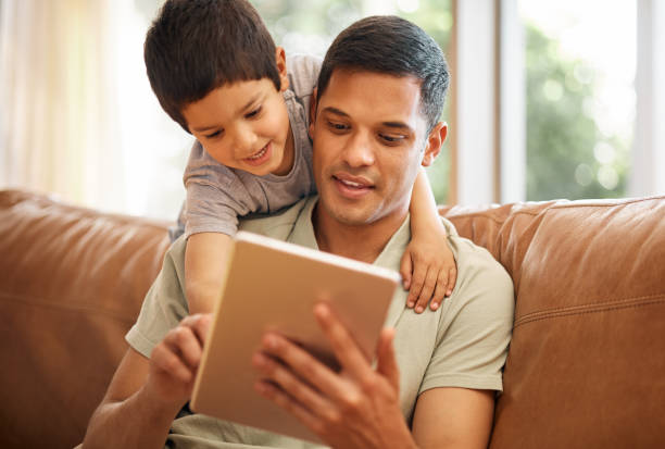 istock Father, boy and child with tablet on sofa for online games, reading ebook story and elearning multimedia. Man, dad and happy kid streaming cartoon, movies or digital technology in living room at home 1662906327