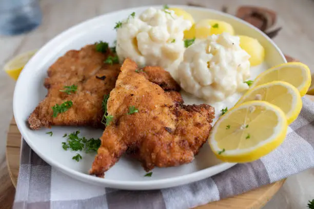 Wiener schnitzel with cauliflower, bechamel sauce and boiled potatoes. Traditional cuisine. Served ready to eat on a plate. Closeup, front view