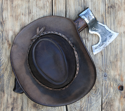 cowboy hat and ax on old wooden background